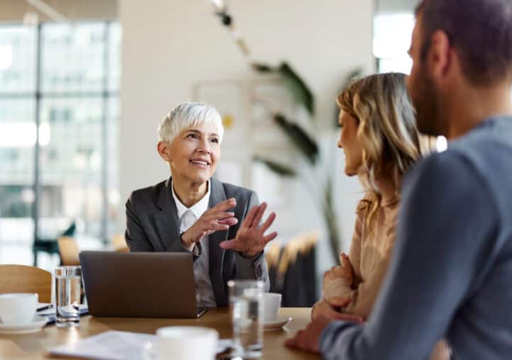 happy female insurance agent talking to a couple on a meeting in the office.