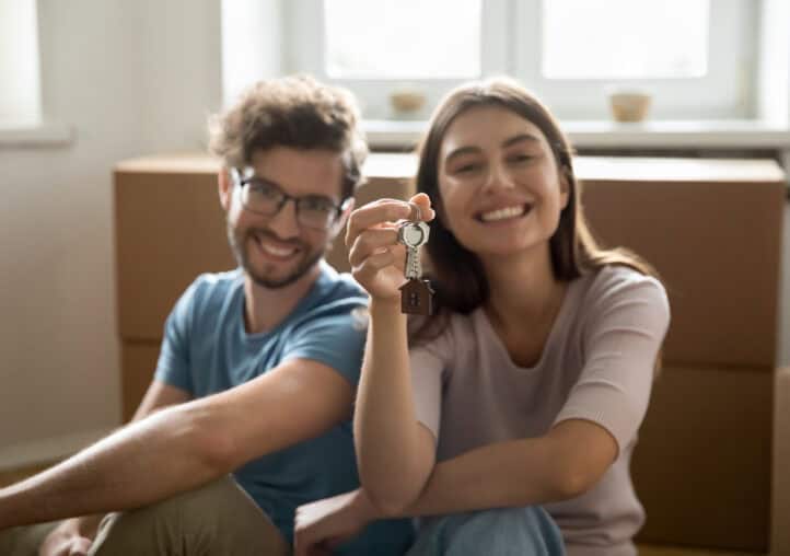 happy young couple showing keys from hew home together