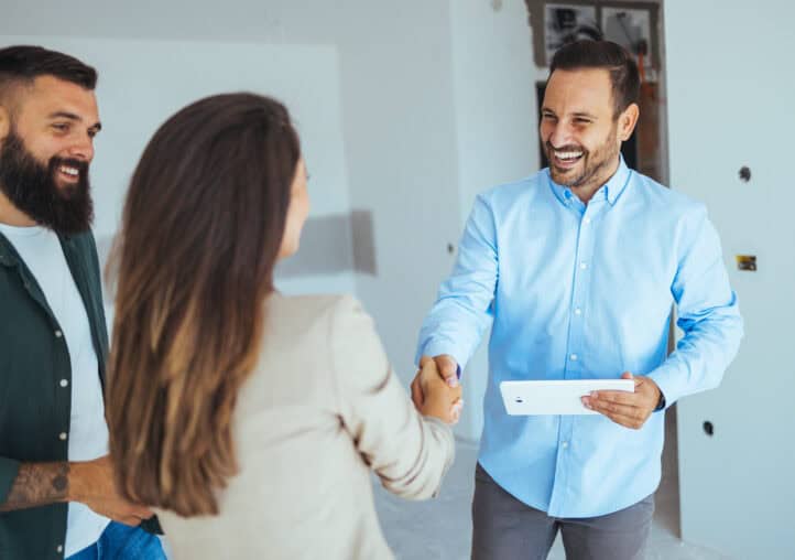 estate agent greeting couple during visit to new home