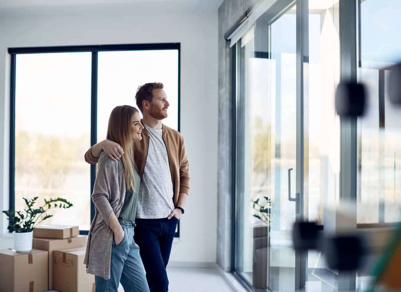 young embraced couple looking through the window of their new apartment.