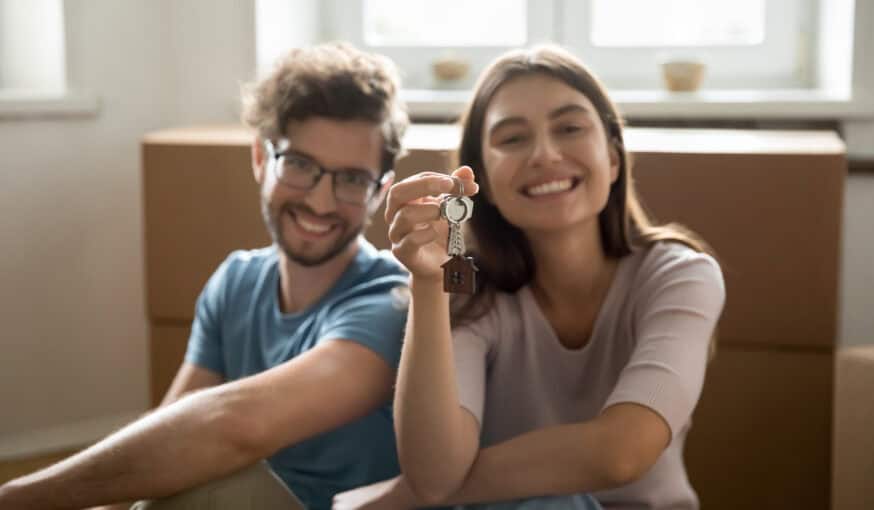 happy young couple showing keys from hew home together