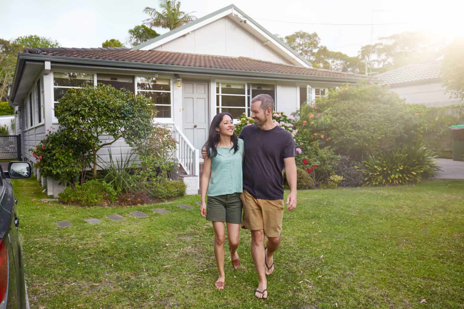 happy mixed race couple walking outside their front yard garden
