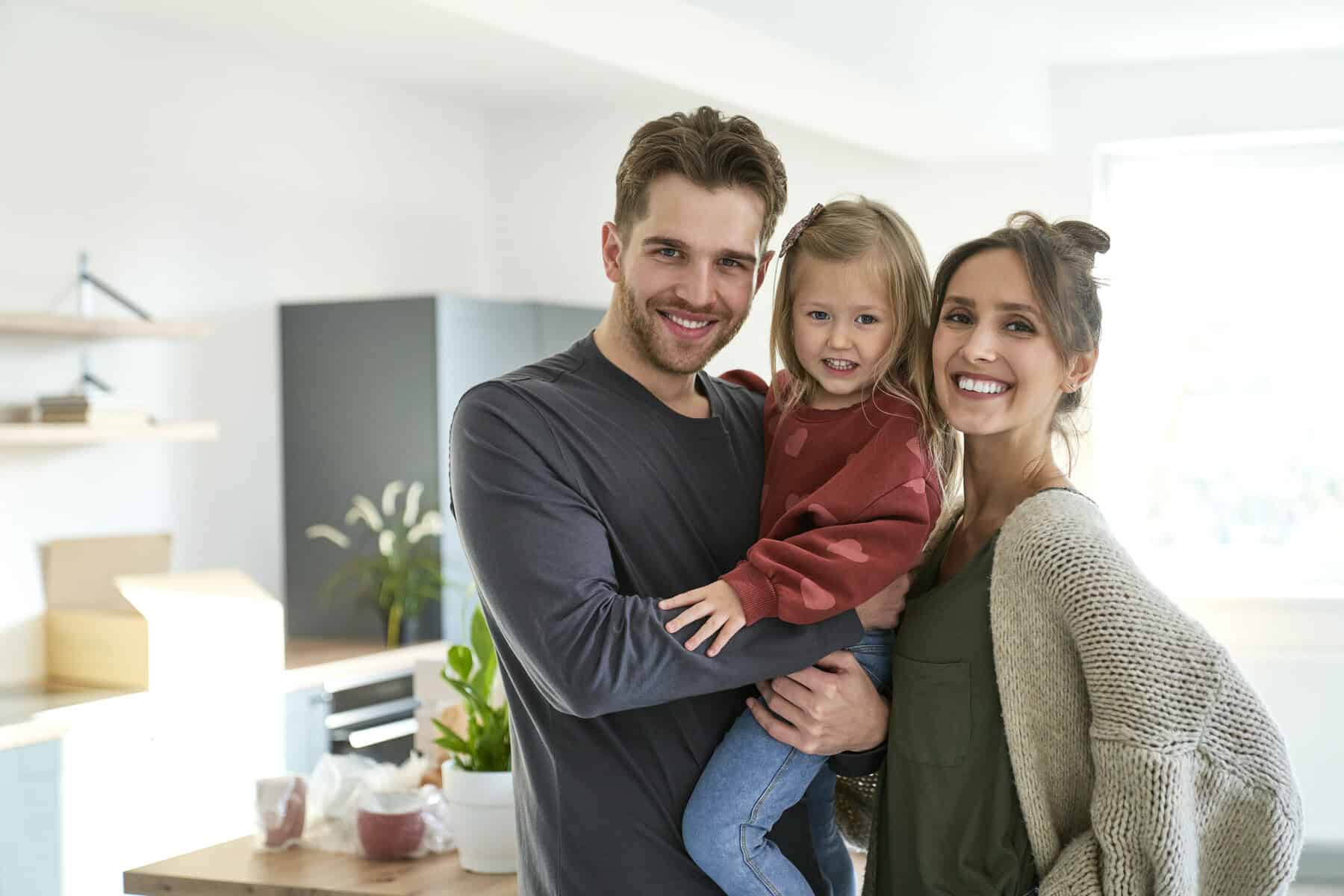 portrait of happy caucasian family with daughter in a new apartment