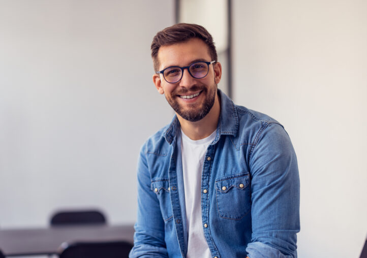 young confident entrepreneur sitting in modern office smiling and looking at camera.