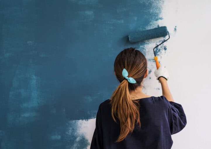 young asian happy woman painting interior wal
